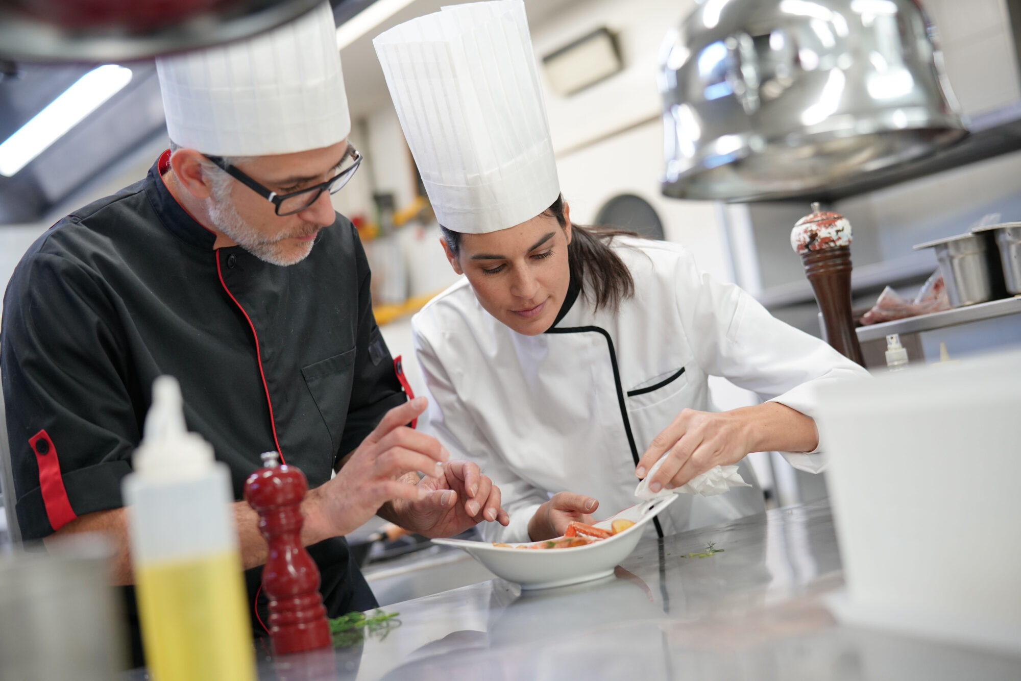 Professional cook chefs in kitchen improving dish composition